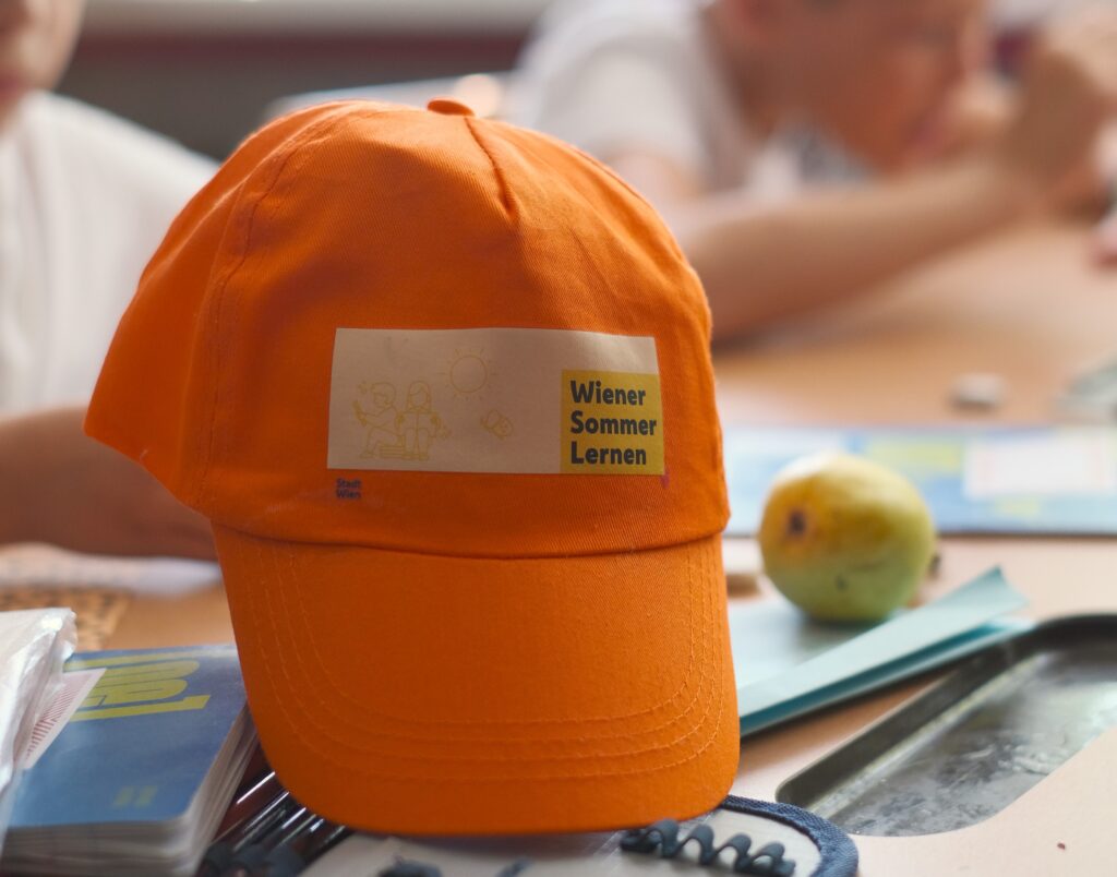 Kappe "Wiener Sommer Lernen" 2024 liegt auf einem Schultisch