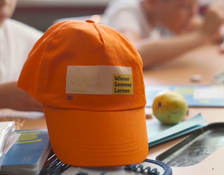 Kappe "Wiener Sommer Lernen" 2024 liegt auf einem Schultisch